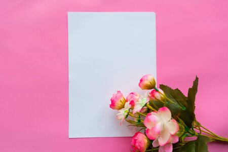 White mock up paper blank and bouquet of flowers on pink background. Valentine's Day or Mother's Day greeting cardの写真素材