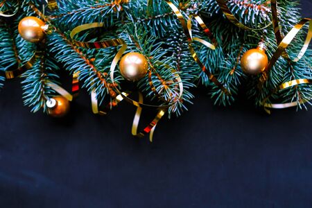 Blue spruce branches with golden baubles and ribbons on black background. Flat lay, top view, copy space. Xmas greeting cardの写真素材