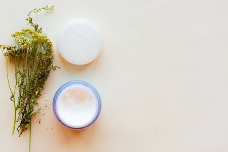 Cream container and herbs on white background, top view, copy space. Natural cosmetic products conceptの写真素材