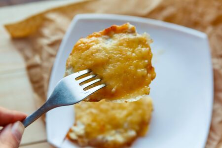 piece of meat in cheese on the forkの写真素材