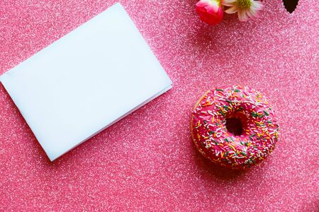 Strawberry donut with colorful sprinkles and white paper blank on pink glitter background.の写真素材