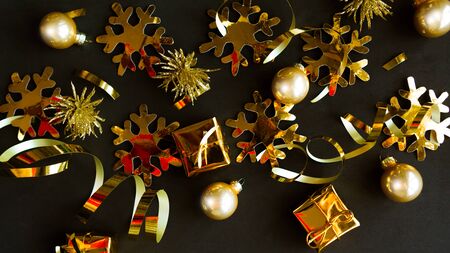 Golden decorations on black background. Flat lay, top view, copy space. Merry Christmas and Happy New Yearの写真素材
