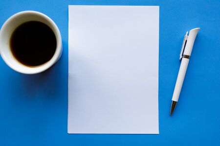 White mockup blank and coffee cup on blue background, flat lay, top viewの写真素材