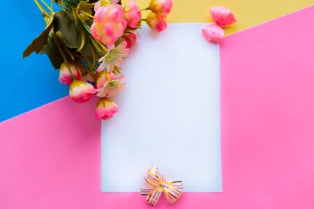 White mock up paper blank and bouquet of flowers on pink and blue background. Valentine's Day or Mother's Day greeting cardの写真素材