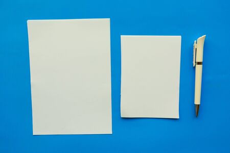 Two white mockup blanks and pen on blue background. Flat lay, top view, copy spaceの写真素材