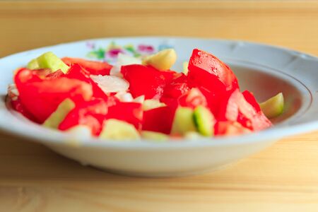 Plate of vegetable salad with fresh tomatoes and cucumbers, closeupの写真素材