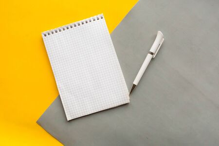 Open notebook and pen on gray and yellow backgroundの写真素材