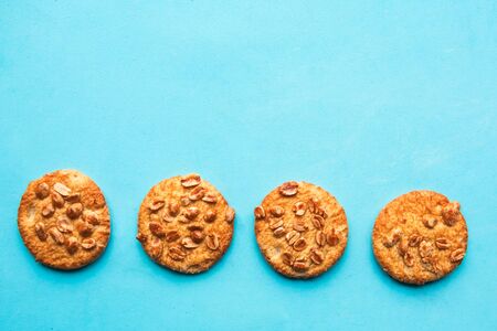 Tasty round cookies with nuts on blue background, top view, copy space, minimalの写真素材