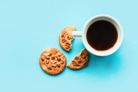 Flat lay photo with coffee cup and cookies with nuts on blue backgroundの写真素材