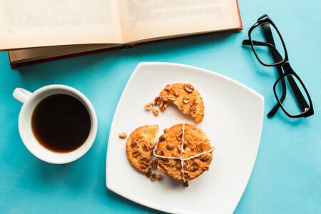 Flat lay photo with coffee cup, cookies, open book and glasses on blue backgroundの写真素材