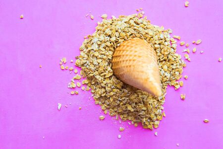 raw oat-flakes on pink background and ice cream coneの写真素材