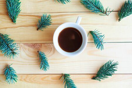 Christmas composition - coffee cup and spruce branches on wooden background, flat lay, top viewの写真素材