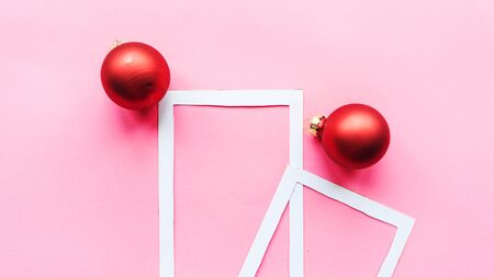 Christmas composition. Photo frame and red baubles on pink background. Christmas, winter, new year concept. Flat lay, top view, copy space
の写真素材