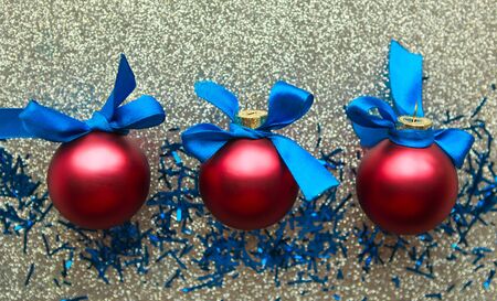 Three red balls with blue bows on silver background, top view. Merry Christmas and Happy New Yearの写真素材