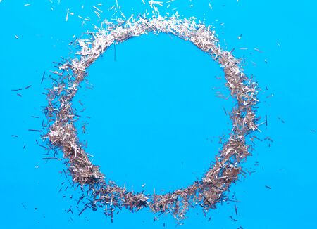 Round silver tinsel frame on bright blue background. Copy space for the textの写真素材