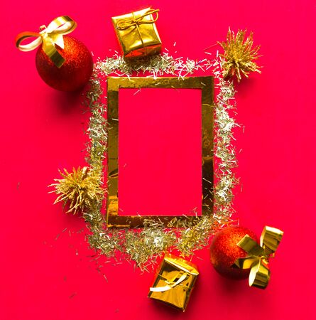Merry Christmas and Happy New Year. Flat lay photo with golden mockup photo frame and Christmas decorations on bright red background. Xmas greeting card, banner. Copy space for the textの写真素材