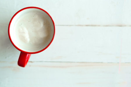 Red coffee cup on wooden background, top view, copy space