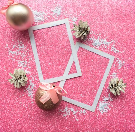White photo frames with Christmas decorations on pink background. Xmas greeting cardの写真素材