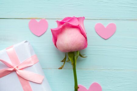Pink rose and gift box on blue wooden background. Valentines Day greeting cardの写真素材