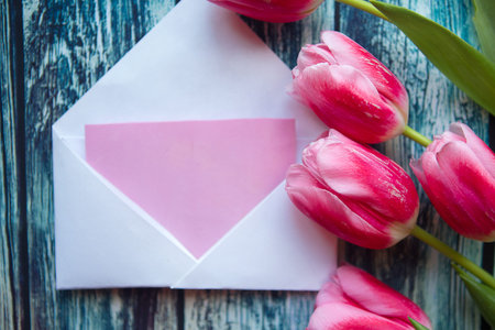 Red tulips and white mockup blank on wooden background. Flat lay, top view, copy space. Easter,...