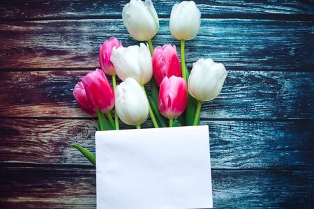 Bouquet of red and white tulips and white mockup blank on wooden background, top view. Copy space for the textの写真素材