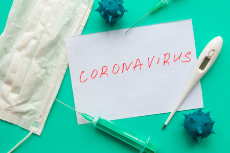 Medical mask and thermometer on green background.  Coronavirus disease covid-19