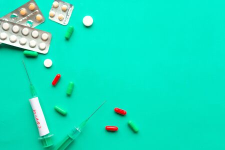 Disposable syringes and pills on green background.  Coronavirus disease covid-19の写真素材