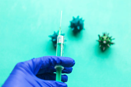 Blue gloved hand holds a syringe. Coronavirus disease covid-19