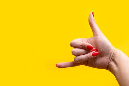 Closeup view of female hand forming gesture call me. Isolated on bright yellow background. Copy space for the textの写真素材