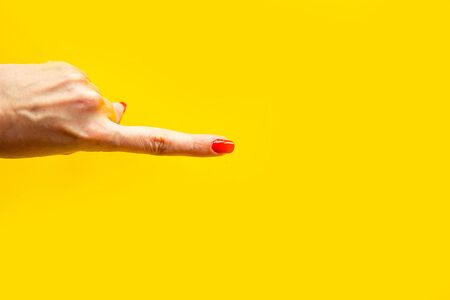Woman's hand shows the point gesture over bright yellow background. Minimal concept. の写真素材