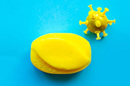 Bright yellow soap bar and positive virus on blue background. Covid-19 conceptの写真素材