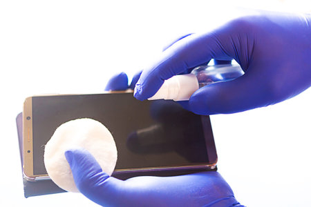 Man in gloves wipes the phone with a cotton sponge. Covid 19 conceptの写真素材