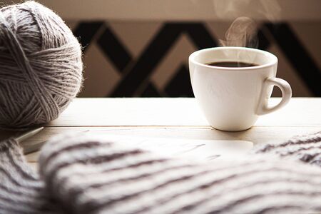 ball of grey thread, knitting and a coffee cup on wooden tableの写真素材