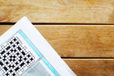 Newspaper with crossword on wooden background. Copy space for the textの写真素材