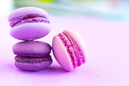 Pink macaroons on purple background, closeup