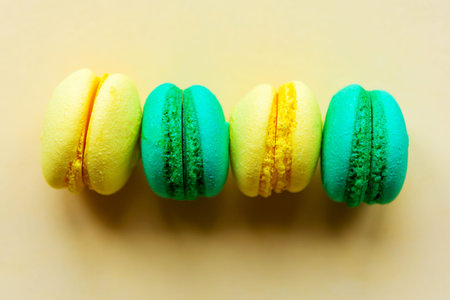 Yellow and green sweet tasty macaroons on yellow background. 