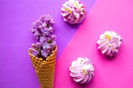 Lilac blooming branch in waffle cone and meringue on geometric purple background. の写真素材