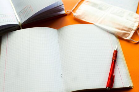 Open notebook, pencil and medical mask on the table. Back to school concept. School quarantine concept. Copy space for the textの写真素材