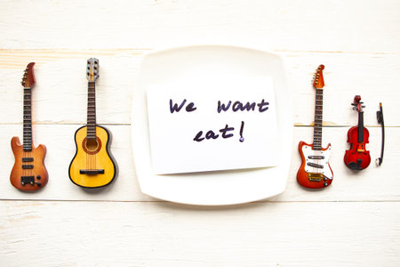 Electric and acoustic guitar and card with message We Want Eat on the plate. Coronavirus music conceptの写真素材