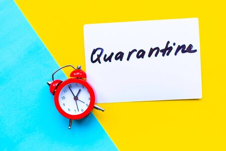 Alarm clock and card with message quarantine on geometric blue and yellow backgroundの写真素材