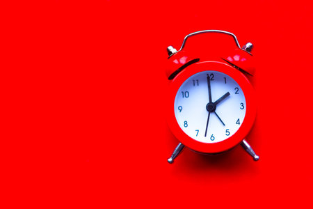 Alarm clock on bright red background. Minimal concept. Copy space for the text