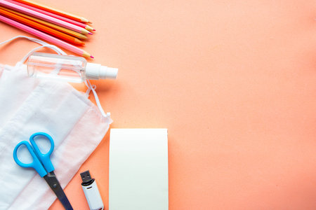 School supplies, medical mask and hand sanitizer on pastel pink background. Back to school concept....