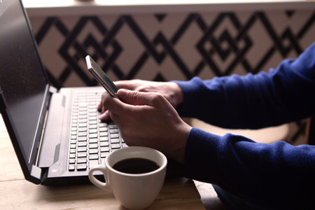 Man works at home and uses a smart phone and a notebook computer. Freelance concept
