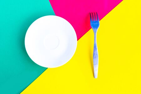 White mockup plate and fork on green geometric background. Copy space for the text. Minimal conceptの写真素材