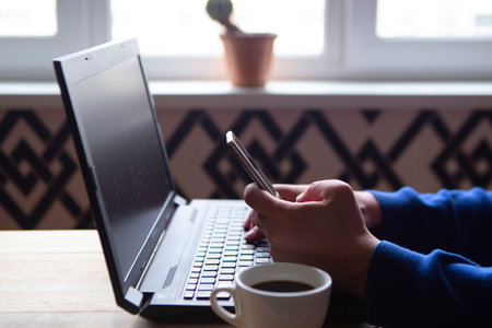The man works at home and uses a smart phone and a notebook computer. Freelance concept