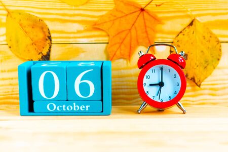 October the 6th. Blue cube calendar with month and date and alarm clock on wooden background.の写真素材