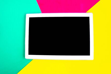 Tablet with black mockup screen on bright geometric red, green and yellow background. Copy space for the text. Minimal conceptの写真素材