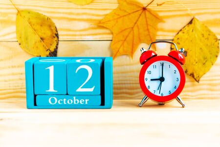 October the 12th. Blue cube calendar with month and date and alarm clock on wooden background.の写真素材