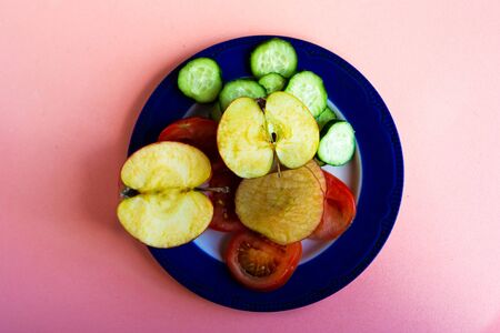 plate with fruit and vegetables on pastel pink background, top viewの写真素材