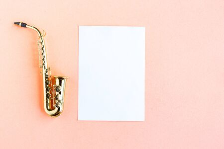 Toy saxophone and white mockup blank on pink background, top view, copy space for the textの写真素材